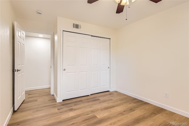 unfurnished bedroom featuring light wood-style flooring, baseboards, visible vents, a ceiling fan, and a closet