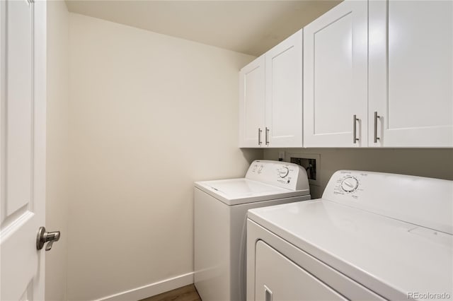 clothes washing area featuring baseboards, cabinet space, wood finished floors, and washer and clothes dryer