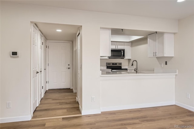 kitchen featuring a sink, light wood-type flooring, baseboards, recessed lighting, and appliances with stainless steel finishes