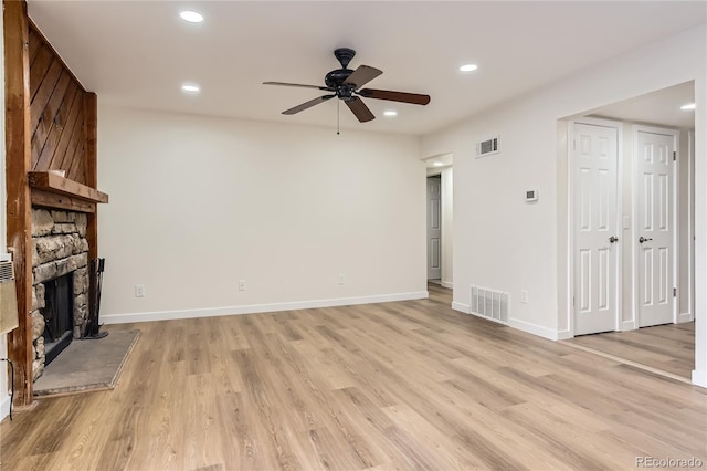 unfurnished living room with a ceiling fan, light wood finished floors, visible vents, and a fireplace
