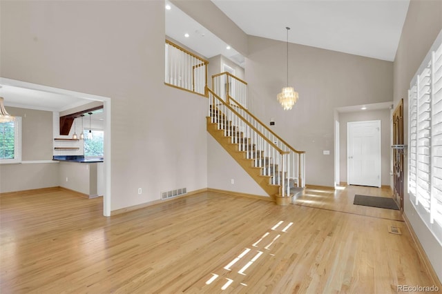 5622 E Weaver Cir, Centennial, CO 80111 - unfurnished living room featuring a chandelier, wood finished floors, stairs, high vaulted ceiling, and recessed lighting