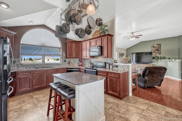 55610 E 40th Ave, Strasburg, CO 80136 - kitchen with lofted ceiling, black appliances, a textured ceiling, ceiling fan, and decorative backsplash