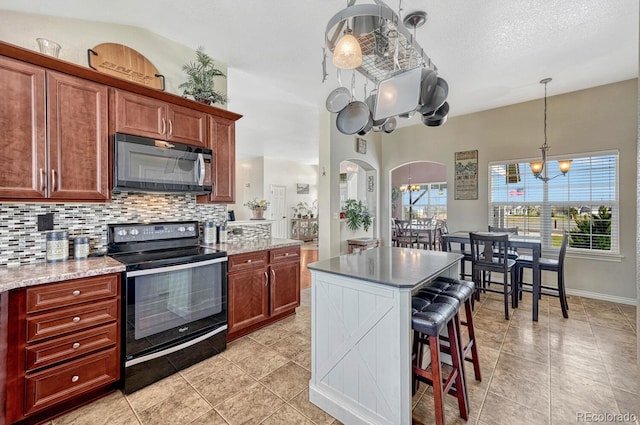 55610 E 40th Ave, Strasburg, CO 80136 - kitchen featuring black appliances, tasteful backsplash, a kitchen bar, light tile patterned flooring, and decorative light fixtures