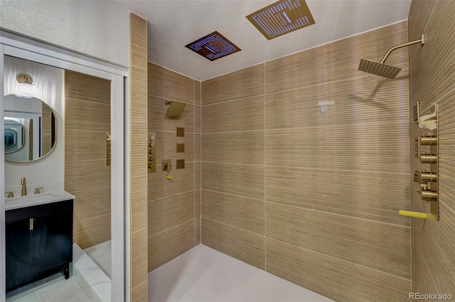 full bath featuring a tile shower, tile patterned flooring, and vanity