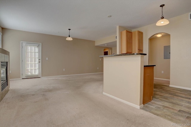 kitchen featuring a tile fireplace, light brown cabinetry, pendant lighting, and light hardwood / wood-style flooring