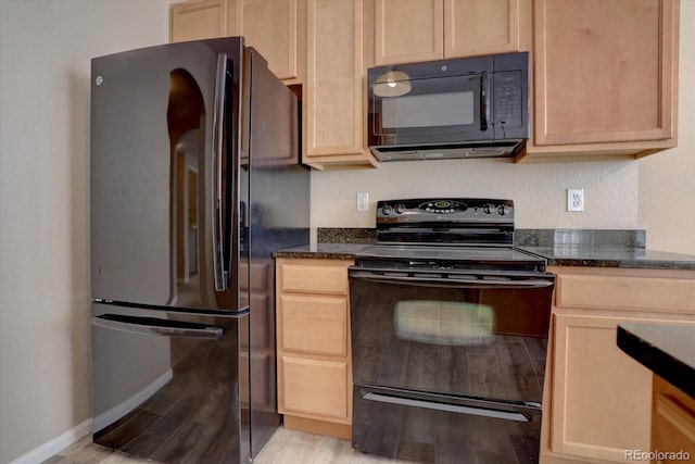 kitchen featuring dark stone countertops, light hardwood / wood-style flooring, black appliances, and light brown cabinets