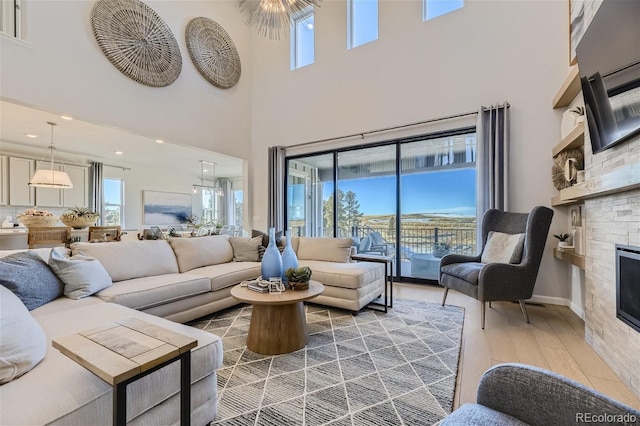 living room with a stone fireplace, a wealth of natural light, and hardwood / wood-style floors