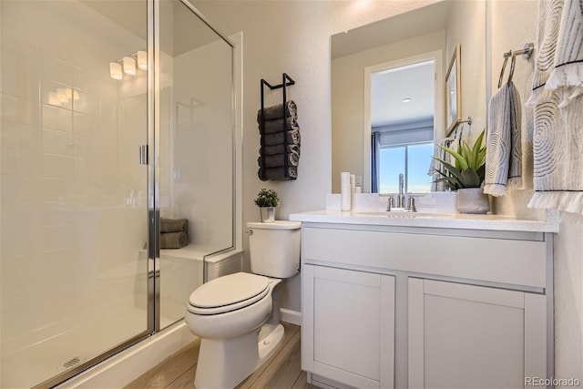 bathroom featuring toilet, hardwood / wood-style floors, vanity, and a shower with door