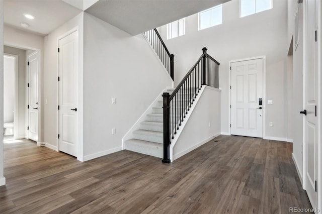 entryway featuring a high ceiling, stairway, baseboards, and wood finished floors