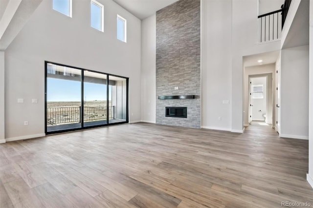 unfurnished living room featuring a healthy amount of sunlight, a fireplace, baseboards, and wood finished floors