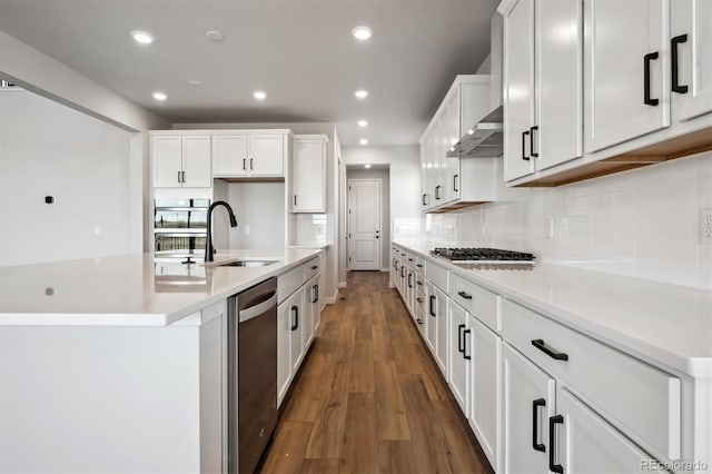 kitchen featuring recessed lighting, wood finished floors, a sink, white cabinets, and appliances with stainless steel finishes