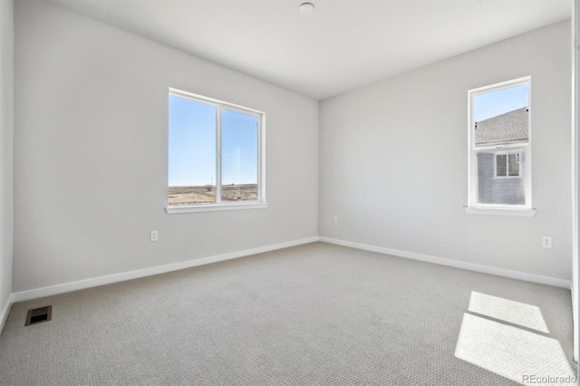 carpeted spare room with visible vents and baseboards