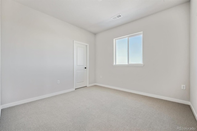 spare room with light colored carpet, visible vents, and baseboards