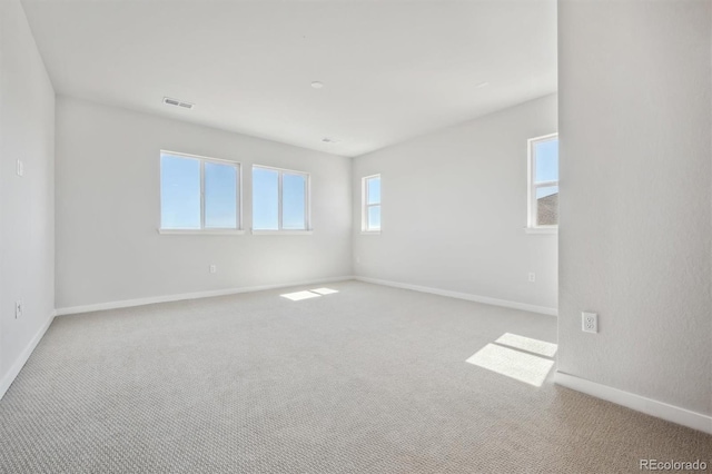 unfurnished room featuring carpet, visible vents, and baseboards