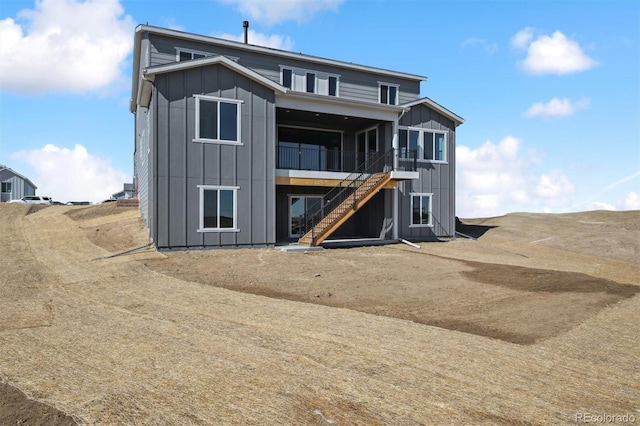 back of house featuring a sunroom, stairs, and board and batten siding