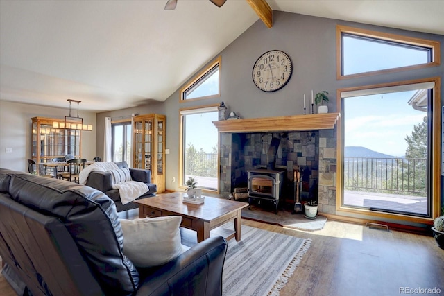 32091 Black Widow Dr, Conifer, CO 80433 - living area featuring wood finished floors, a wood stove, ceiling fan, beam ceiling, and high vaulted ceiling
