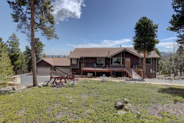 32091 Black Widow Dr, Conifer, CO 80433 - back of property featuring a lawn, a wooden deck, concrete driveway, and a garage