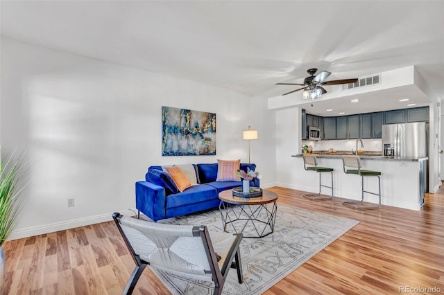 living area featuring visible vents, ceiling fan, light wood-style flooring, and baseboards