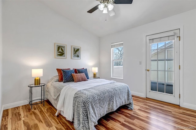 bedroom featuring access to exterior, lofted ceiling, baseboards, and wood finished floors