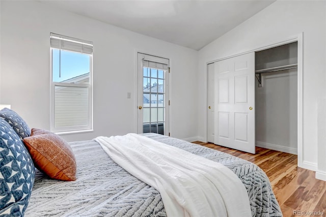 bedroom with lofted ceiling, a closet, baseboards, and wood finished floors