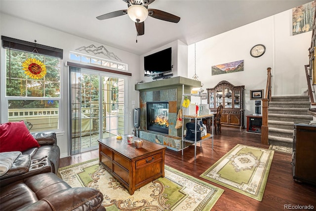 living room featuring ceiling fan, a fireplace, and dark wood-type flooring