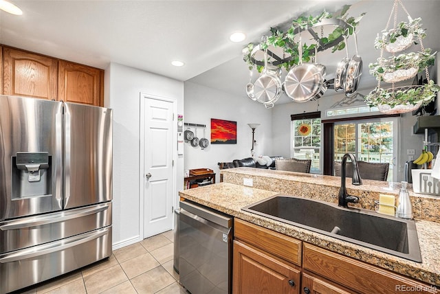 kitchen with light tile patterned floors, light stone countertops, sink, and appliances with stainless steel finishes