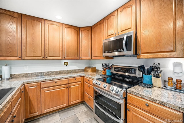 kitchen with light stone counters, sink, light tile patterned flooring, and appliances with stainless steel finishes