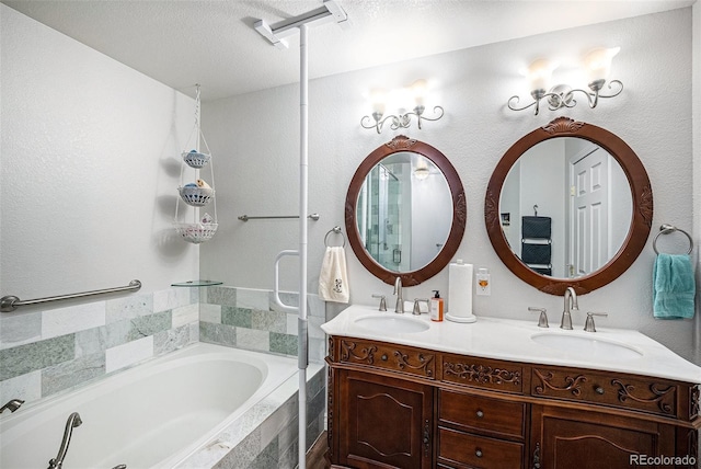 bathroom with a relaxing tiled tub, a textured ceiling, and vanity