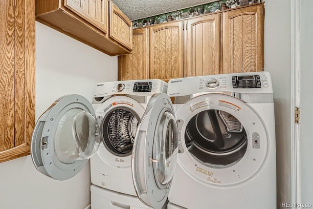 washroom featuring cabinet space, independent washer and dryer, and a textured ceiling