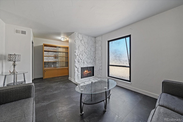 sitting room featuring built in shelves, baseboards, a fireplace, and visible vents