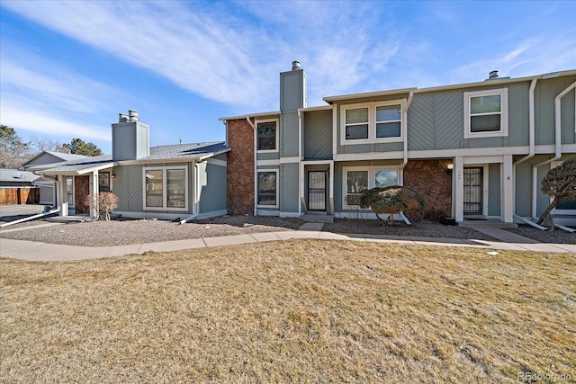 rear view of property featuring a yard and a chimney