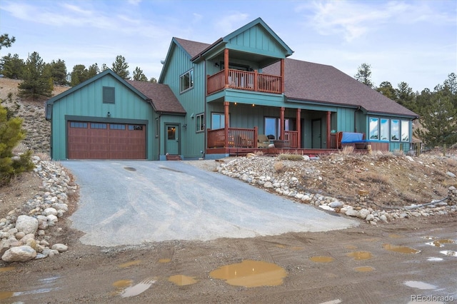 chalet / cabin with driveway, a garage, a shingled roof, a balcony, and a porch