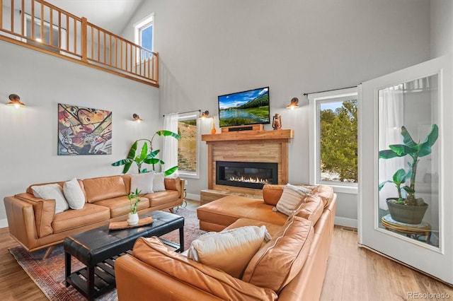 living area with baseboards, wood finished floors, and a glass covered fireplace