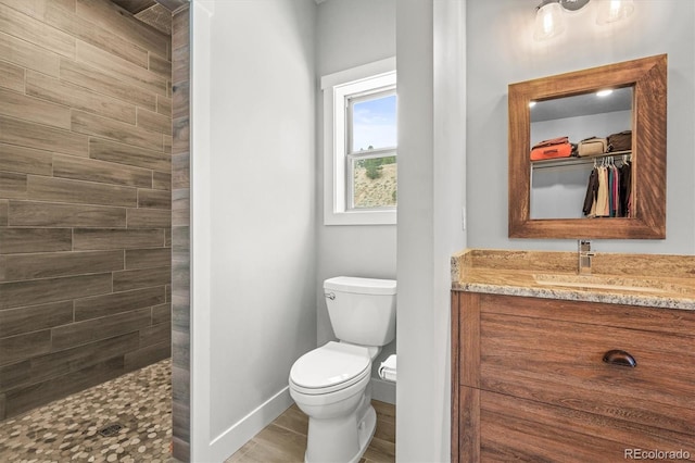 bathroom featuring vanity, walk in shower, toilet, and baseboards