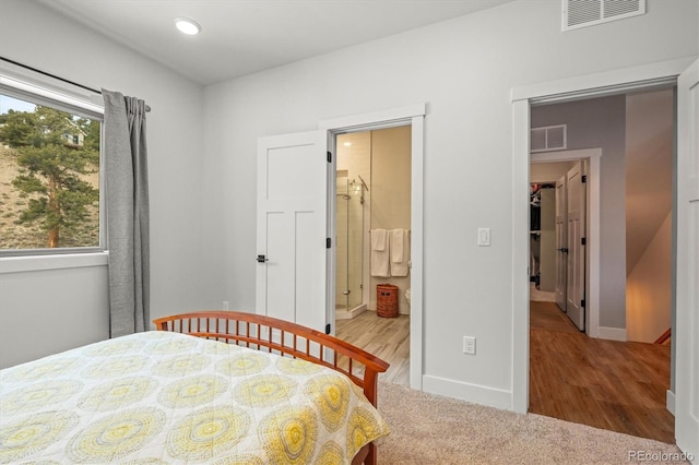 carpeted bedroom with a spacious closet, multiple windows, and visible vents