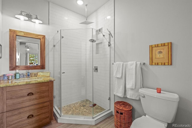 full bathroom featuring toilet, a stall shower, wood finished floors, and vanity