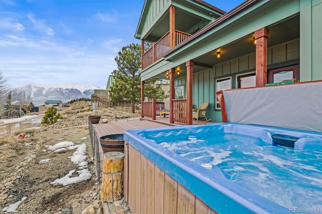 view of patio featuring a balcony, a hot tub, and a deck with mountain view