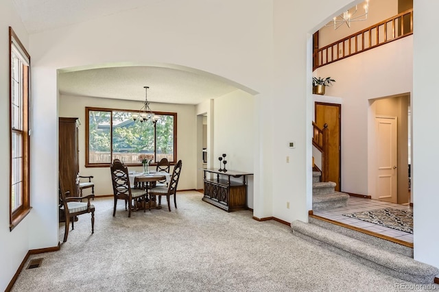 7166 Newhall Dr, Highlands Ranch, CO 80130 - carpeted dining room featuring a chandelier, arched walkways, stairway, and a towering ceiling