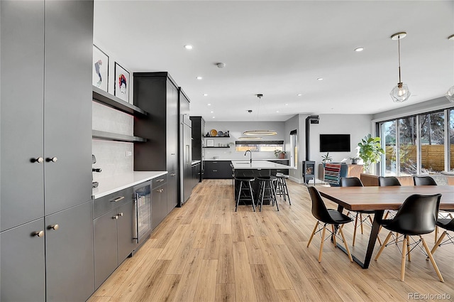 kitchen with a breakfast bar, light countertops, light wood-type flooring, open shelves, and decorative light fixtures