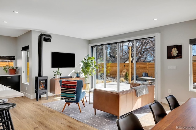 living area featuring a wood stove, light wood-type flooring, baseboards, and recessed lighting