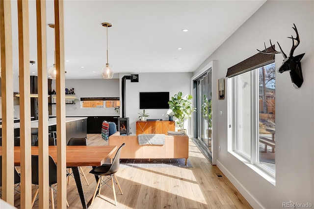 interior space with recessed lighting, visible vents, a wood stove, light wood-type flooring, and baseboards