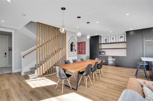 dining space featuring wine cooler, light wood-style flooring, recessed lighting, stairway, and a bar