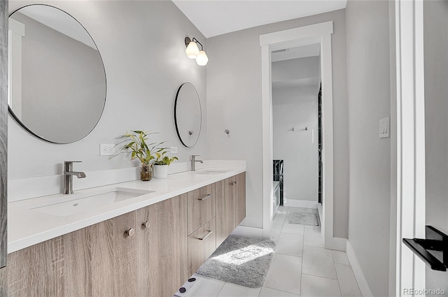 bathroom with tile patterned floors, a sink, baseboards, and double vanity