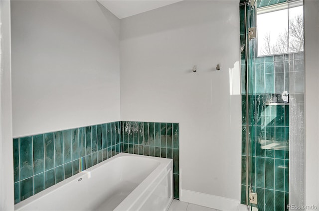 bathroom with tile patterned floors, baseboards, and a bath