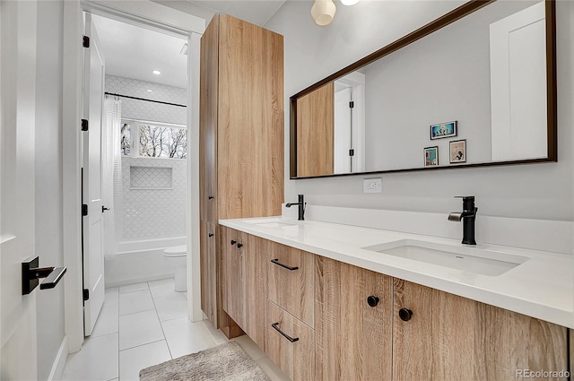 bathroom with double vanity, toilet, a sink, and tile patterned floors