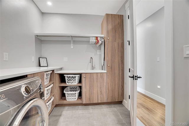 clothes washing area with washer / dryer, baseboards, and a sink