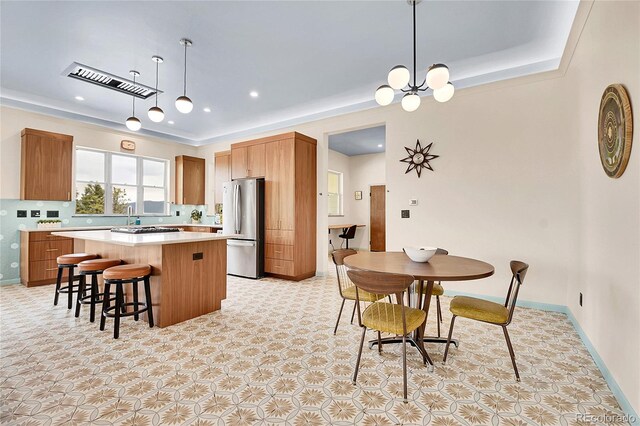 1023 Chippewa Rd, Jefferson, CO 80456 - kitchen with stainless steel appliances, a kitchen island, light countertops, brown cabinets, and a kitchen bar