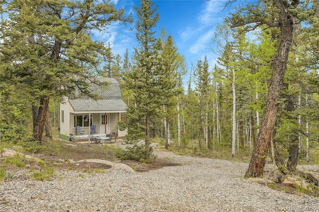 1023 Chippewa Rd, Jefferson, CO 80456 - view of front of house with covered porch, roof with shingles, and a wooded view
