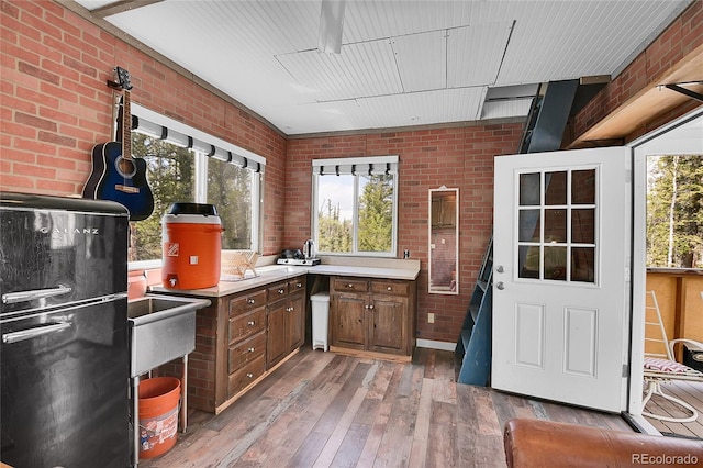 1023 Chippewa Rd, Jefferson, CO 80456 - kitchen featuring brick wall, healthy amount of natural light, light wood-style flooring, light countertops, and freestanding refrigerator