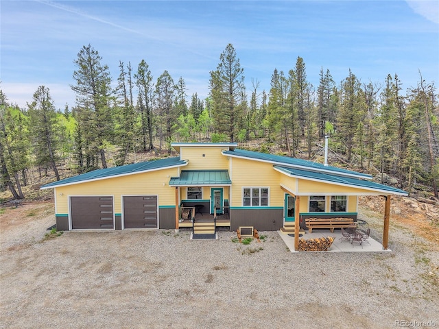1023 Chippewa Rd, Jefferson, CO 80456 - view of front facade with dirt driveway, a wooded view, metal roof, and a deck